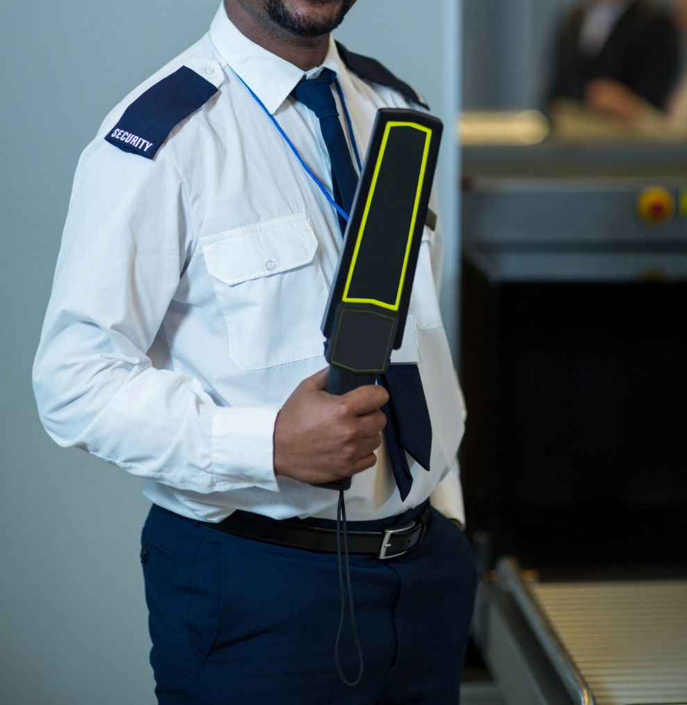 smiling-airport-security-officer-holding-metal-detector-airport-terminal (1)